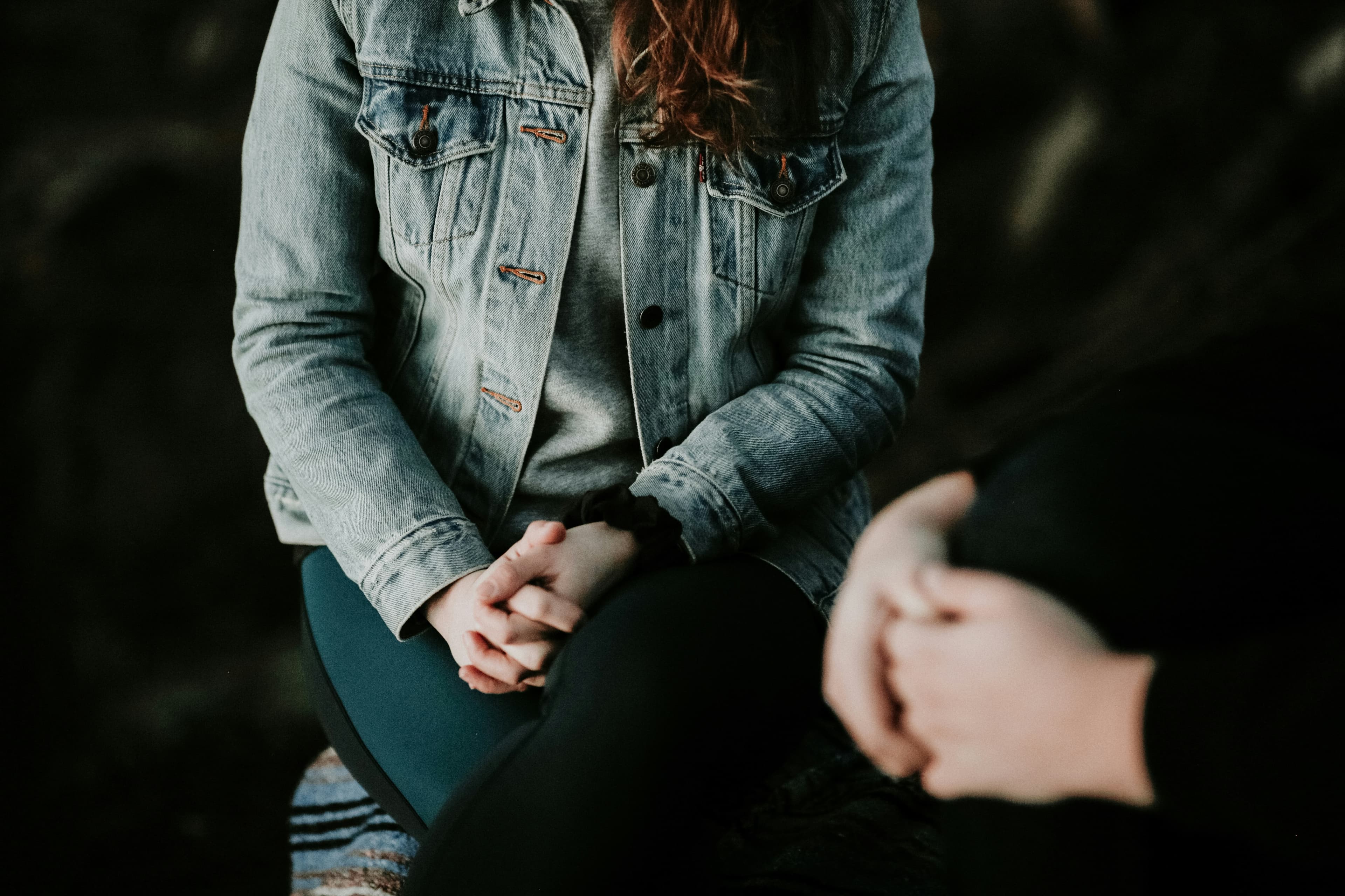 Person in a denim jacket sitting across from a therapist